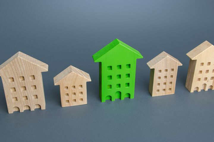 Green residential building among houses. Environmentally friendly, energy efficient and zero carbon emissions. Search for the best option to buy an apartment. Net Zero Carbon neutrality. High quality