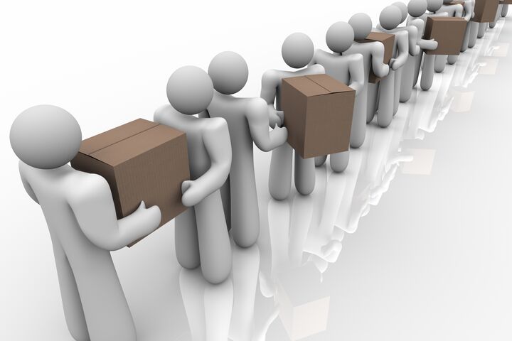 A string of people carrying and handing off cardboard boxes and packages to represent logistics, delivery and organized shipping of materials needed in business