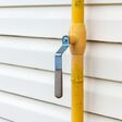 Yellow gas pipe with manual valve on the wall of the house