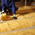 Man installing thermal insulation layer under the roof, using mineral glass wool