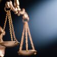 Close up on the scales of justice on a small bronze statue over a blue background with copy space conceptual of law and order
