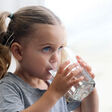 Mädchen trinkt Wasser aus einem großen Glas