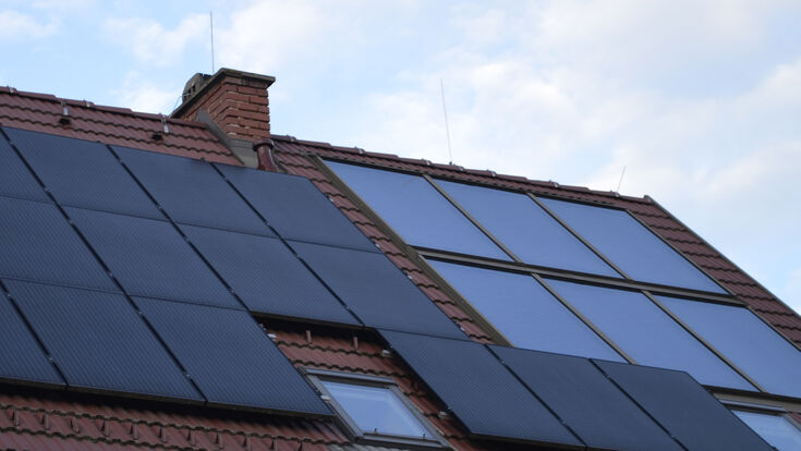 © HLK/ E. Herrmann Solarthermie-Kollektor und Photovoltaik-Paneele auf einem Dach