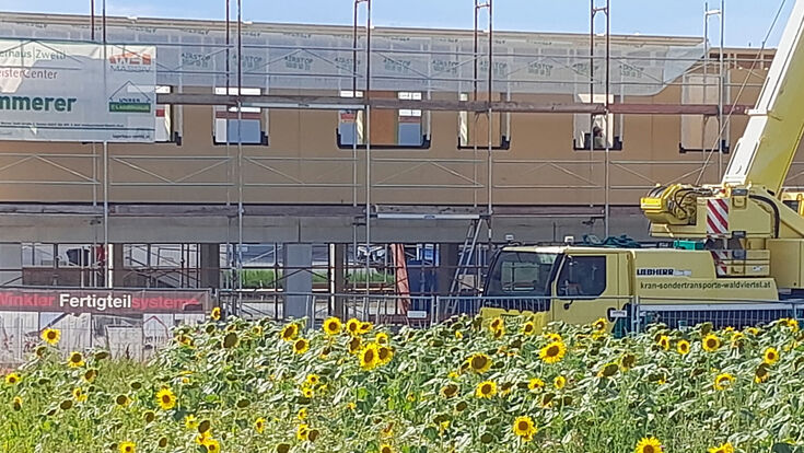 Baustelle mit Hausfront im Rohbau und einem Kran