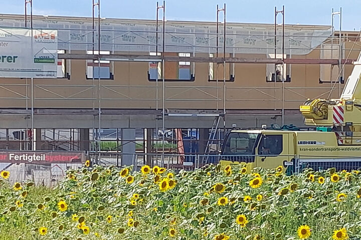 Baustelle mit Hausfront im Rohbau und einem Kran