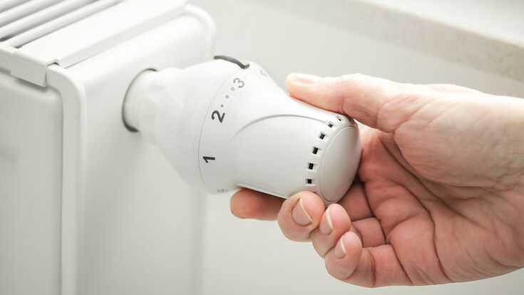 hand adjusting the temperature of heating radiator