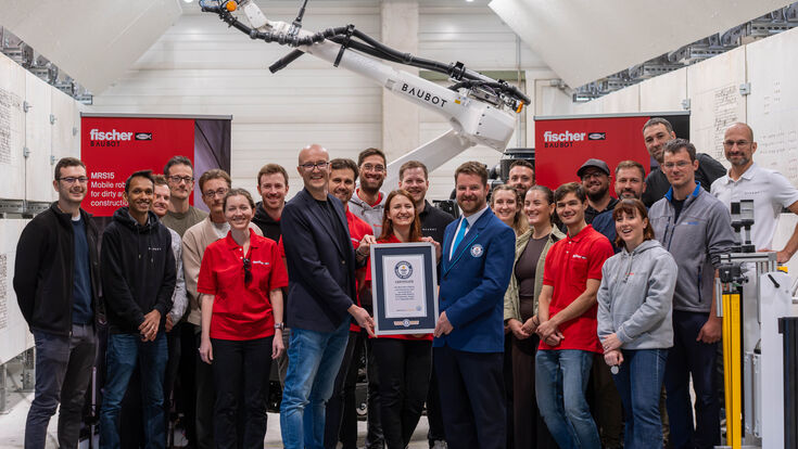 fischer BauBot Team mit Guiness World Records-Urkunde und Bauroboter im Hintergrund
