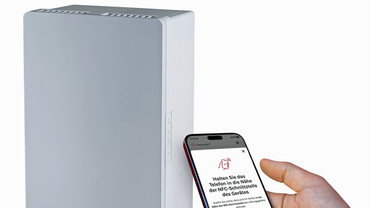 Neues, dezentrales Lüftungsgerät PluggCompact und ein Mobiltelefon, mit dem Fachleute das Gerät (mit App) konfigurieren können.