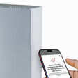 Neues, dezentrales Lüftungsgerät PluggCompact und ein Mobiltelefon, mit dem Fachleute das Gerät (mit App) konfigurieren können.