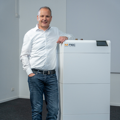 M-TEC, Mann lehnt auf einer Indoor-Wärmepumpe