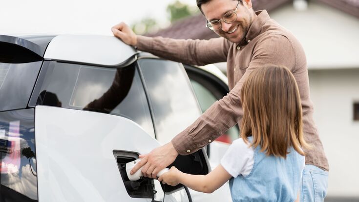 Mann und Kind beim Aufladen eines Elektroautos