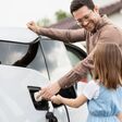 Mann und Kind beim Aufladen eines Elektroautos