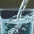 Glas, in das Wasser strömt und digitale Zeichen als Hintergrund