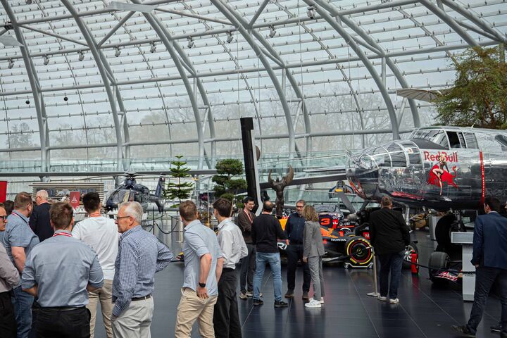 Personen begutachten ein Flugzeug, einen Hubschrauber und ein Formel 1-Auto im Red Bull Hangar-7
