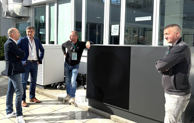 Fachleute stehen vor der Außeneinheit der Wärmepumpe aroTHERM perform bei Vaillant in Wien
