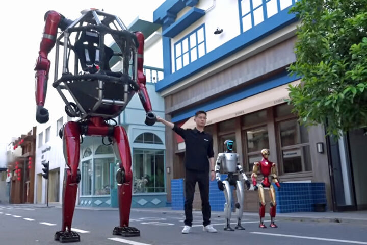 bemannbarer Roboter GD01 (li.), ein Mensch, und zwei Humanoid-Roboter von Unitree Robotics